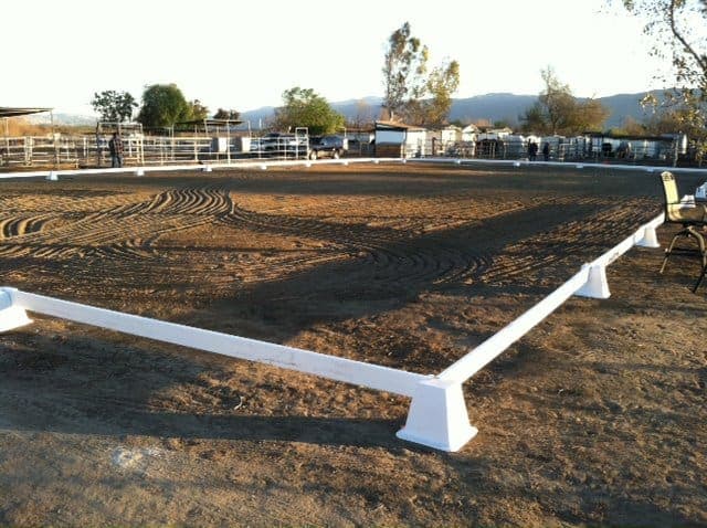 The white-railed dressage court at sunset, freshly dragged